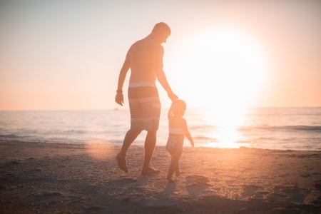 man and child walking to ocean